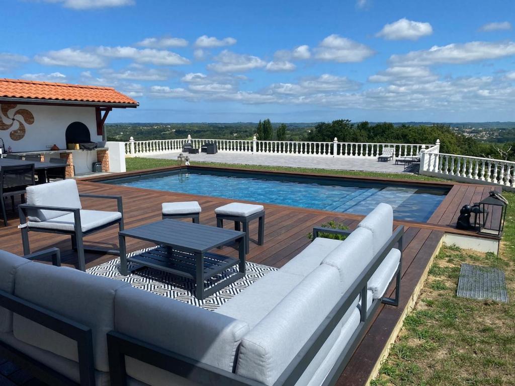 a swimming pool with a couch and a table next to it at Maison Pays Basque in Briscous