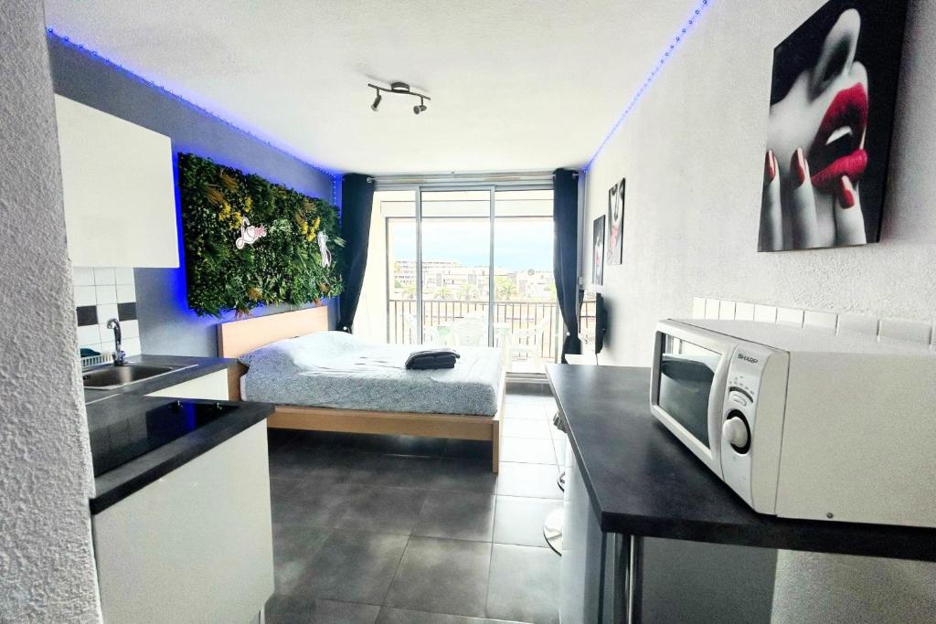 une chambre avec un lit et une cuisine avec un four micro-ondes dans l'établissement Naturiste Cap d'Agde Héliopolis F 47, au Cap d'Agde