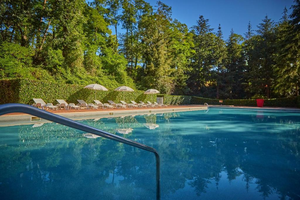 une piscine avec chaises longues et parasols dans l'établissement Camping Parc des Roches, à Saint-Chéron