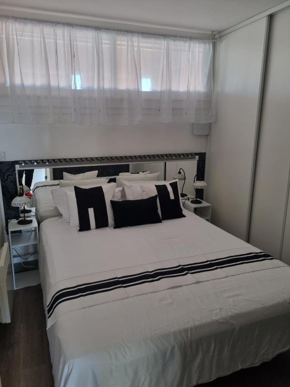 - une chambre avec un grand lit et des oreillers noirs et blancs dans l'établissement Naturiste Cap d'Agde Port Ambonne 204, au Cap d'Agde
