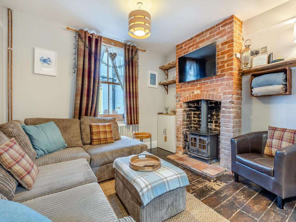 a living room with a couch and a fireplace at Melrose Cottage in Cromer