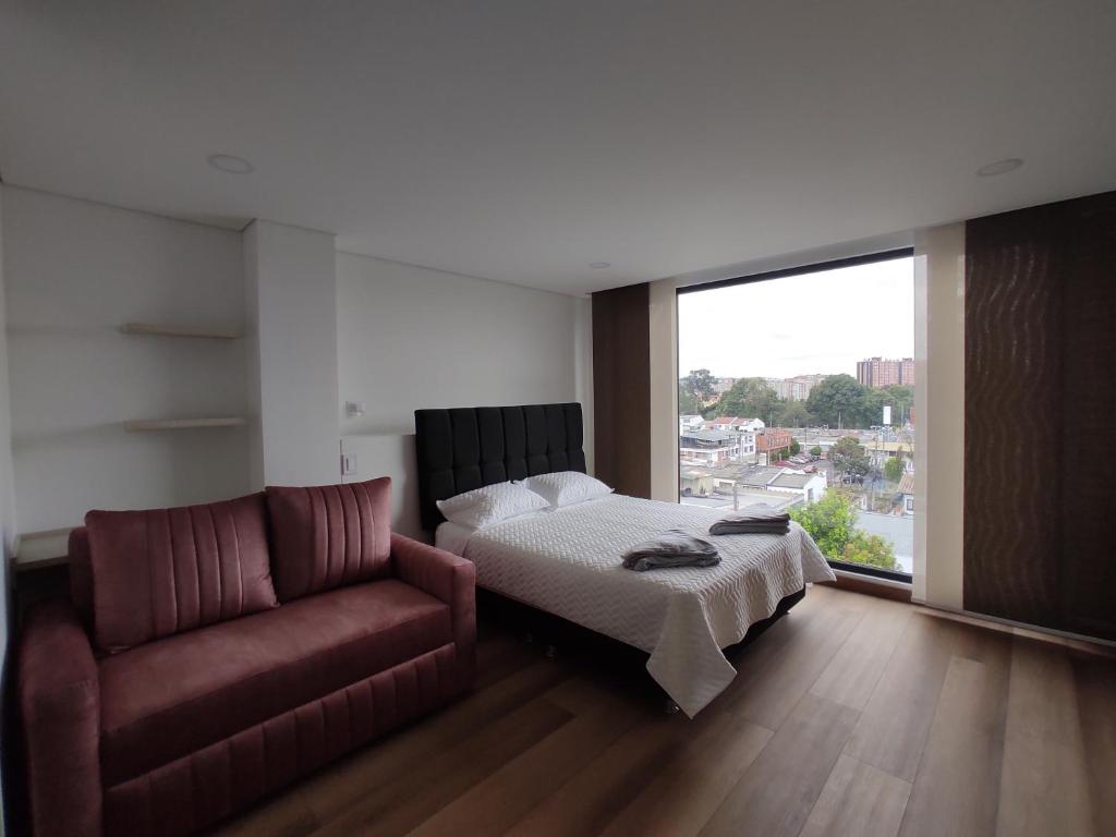a bedroom with a bed and a couch and a window at Modelia Living & Parking SAS in Bogotá