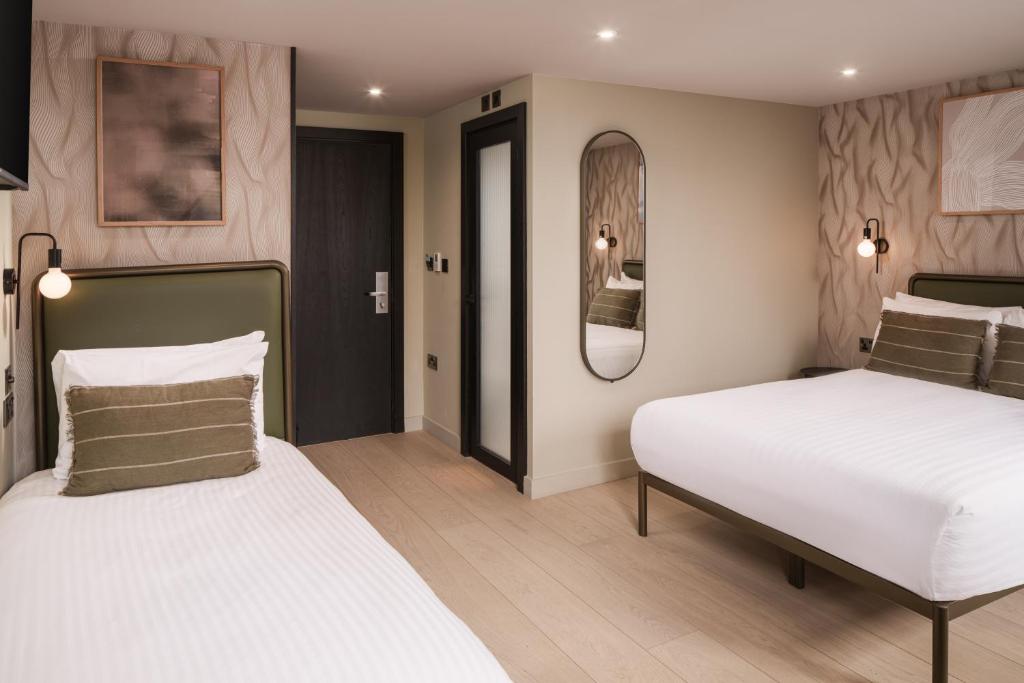 a bedroom with two beds and a mirror at Central Park Hotel in London