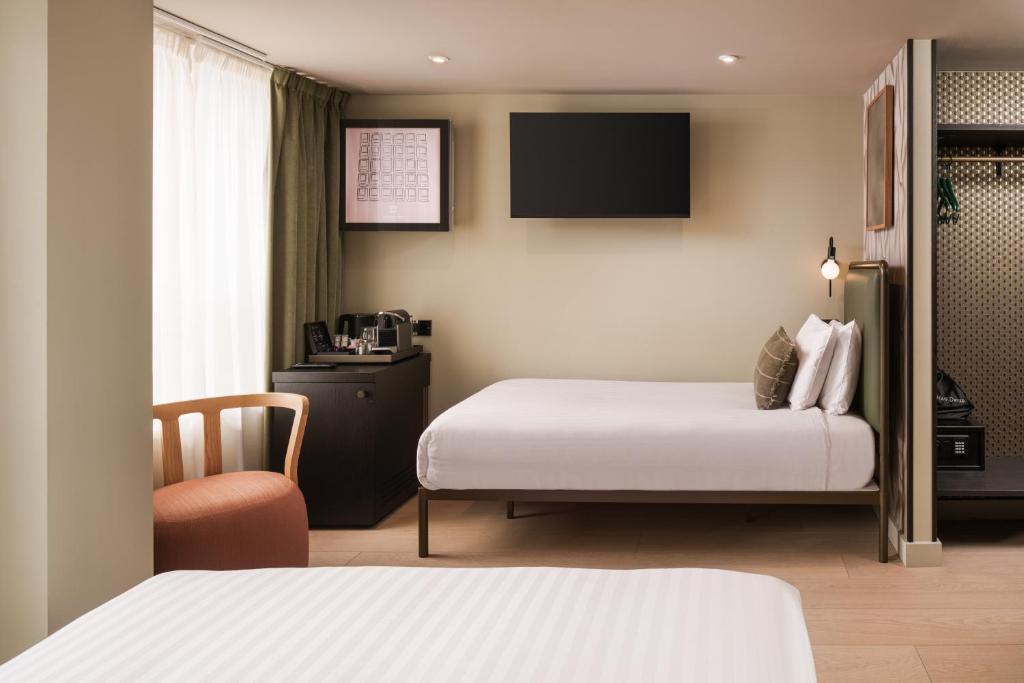a hotel room with two beds and a chair at Central Park Hotel in London