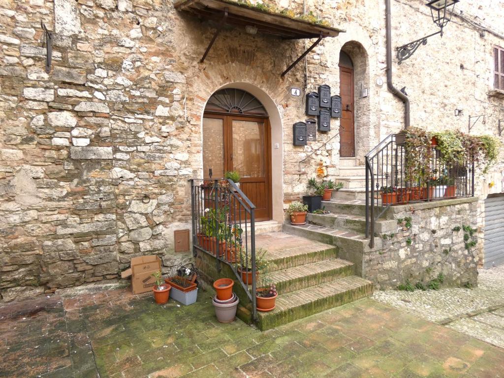 a stone building with stairs and a door with potted plants at Il Loft dell' americano in Narni