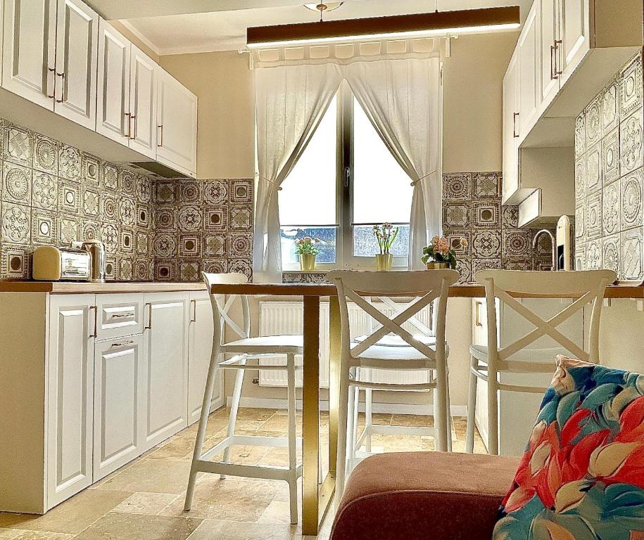a kitchen with white cabinets and a table and chairs at Apartament Alexandru Saturn in Saturn