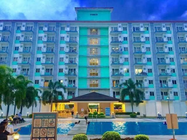 a large building with a pool in front of it at King Elite Condo Hotel Field Residences Near NAIA Airport in Manila