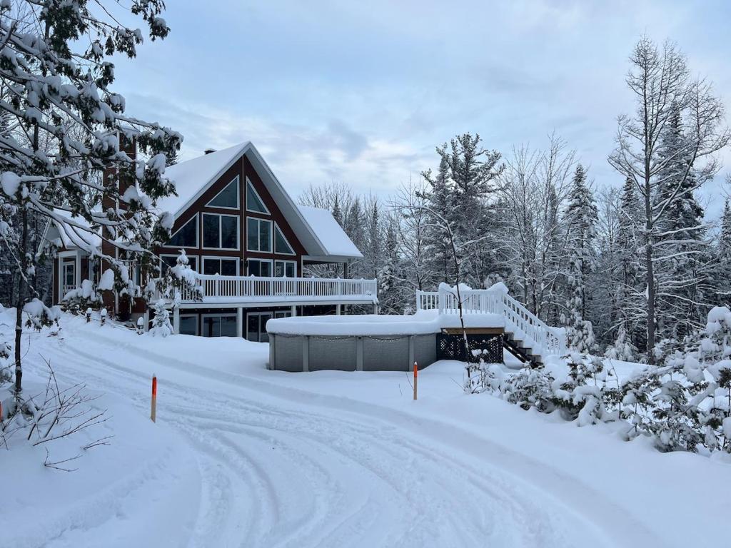 a house covered in snow with a snow covered driveway at Chalet Desroy in Chertsey