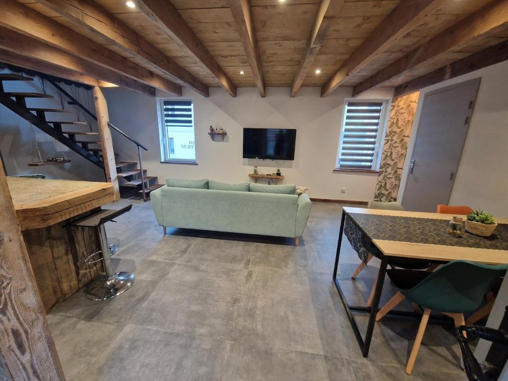 un salon avec un canapé vert et une télévision dans l'établissement L'Escouflette, à Rochesson