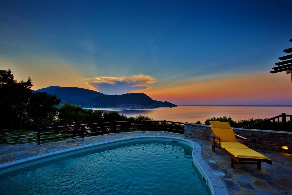 a swimming pool with a chair and a view of the ocean at Porto Skopelos Villas in Skopelos Town