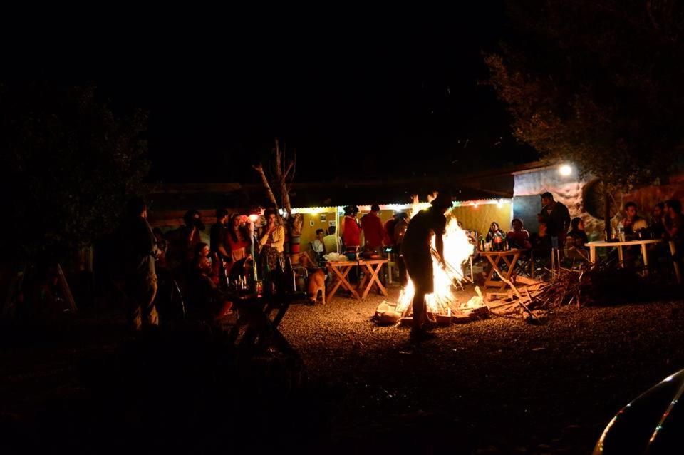 a crowd of people standing around a fire pit at El Farolito Hostel in Tilcara