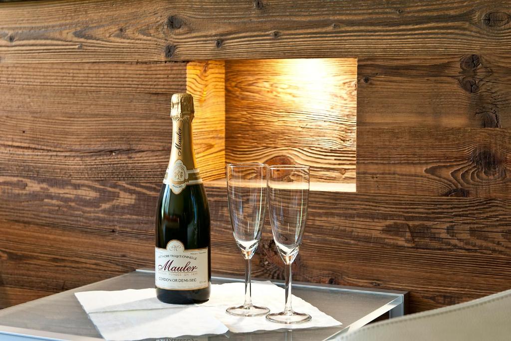 eine Flasche Champagner und zwei Gläser auf dem Tisch in der Unterkunft Studio Castor Zermatt in Zermatt