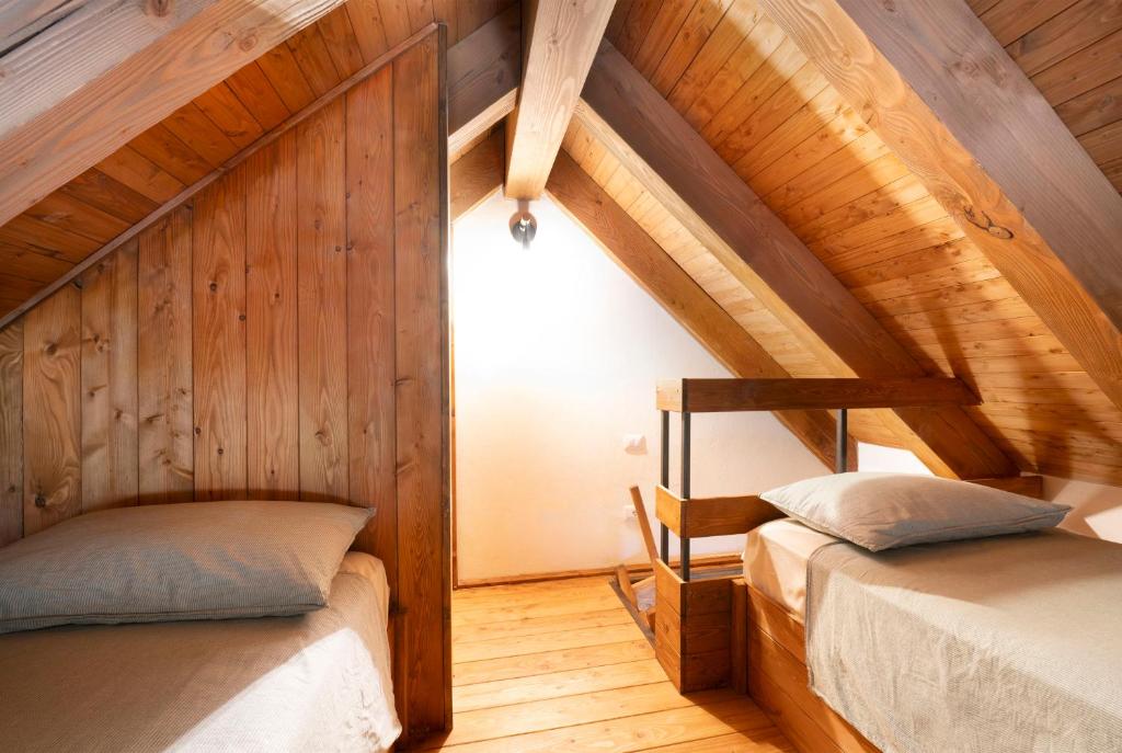 two beds in a room with wooden walls at Baita Iadi - Villaggio dei Crodini in Cravegna