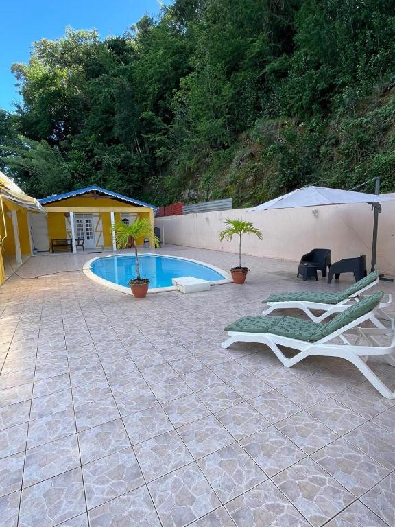 un patio con sedie a sdraio e una piscina di Studio Cosy avec espace piscine à la villa Boucard a Le Gosier