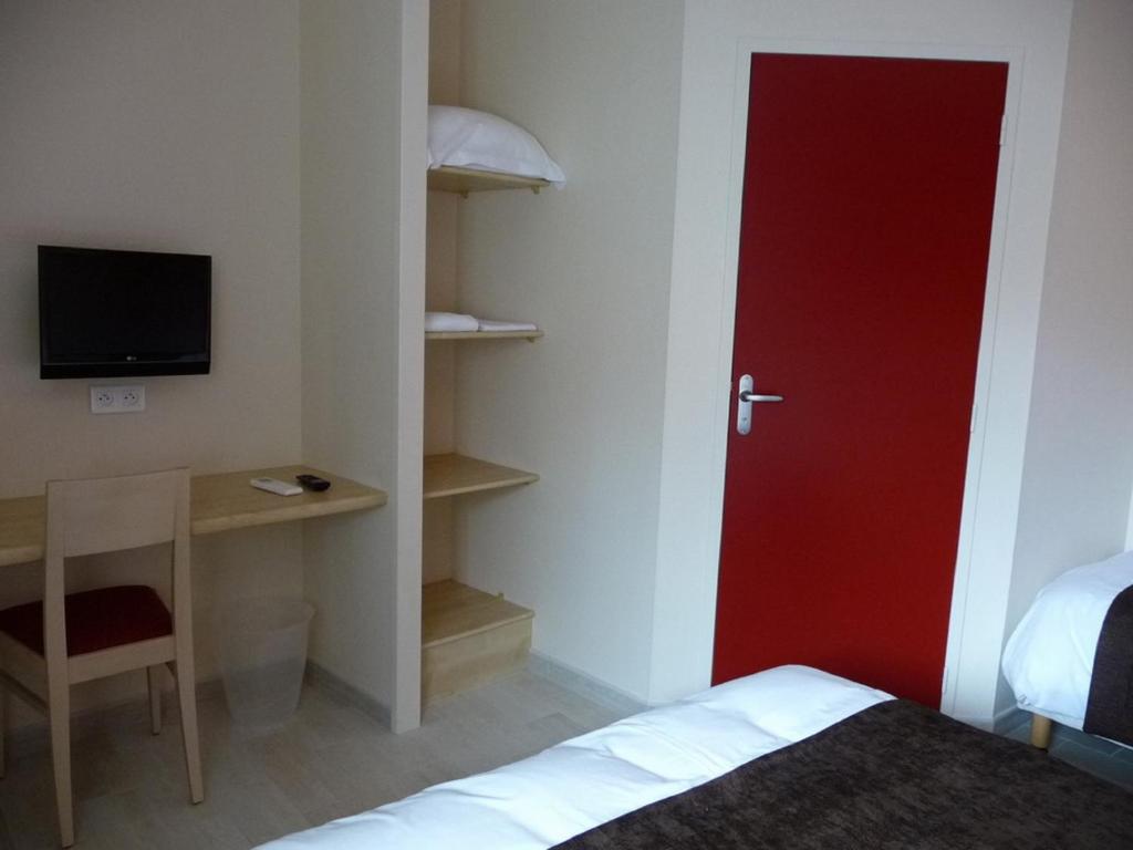 a room with a red door and a desk and a bed at La Godinière in Cholet