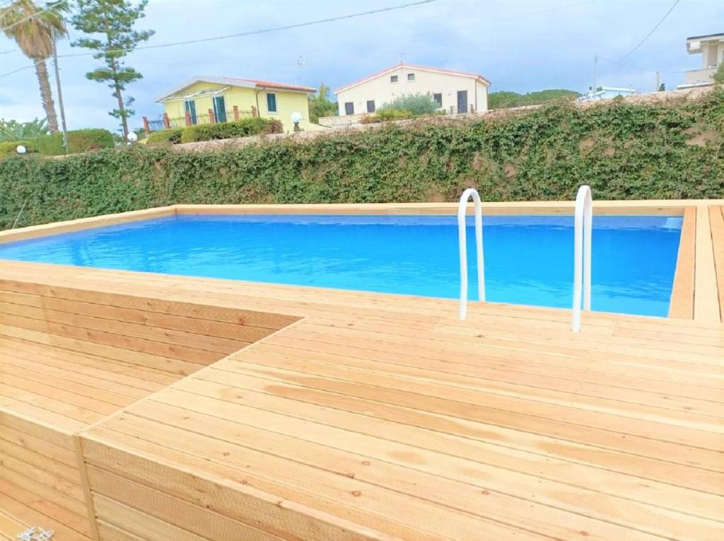 a pool with a wooden deck and a blue swimming pool at Villa La Pineta in Plemmirio