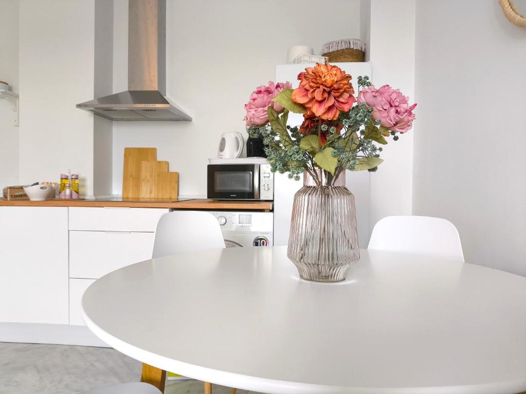 eine Vase mit Blumen auf einem weißen Tisch in der Küche in der Unterkunft Apartamento acogedor - piscina - parking in Sevilla