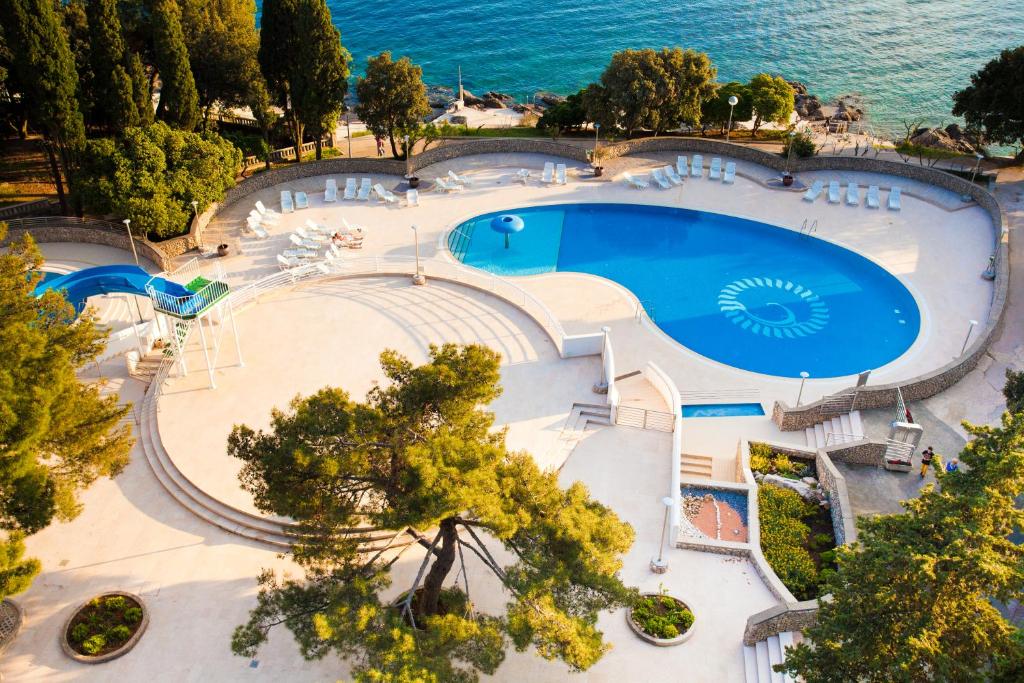 an overhead view of a large swimming pool next to the ocean at Hotel Dražica - Hotel Resort Dražica in Krk