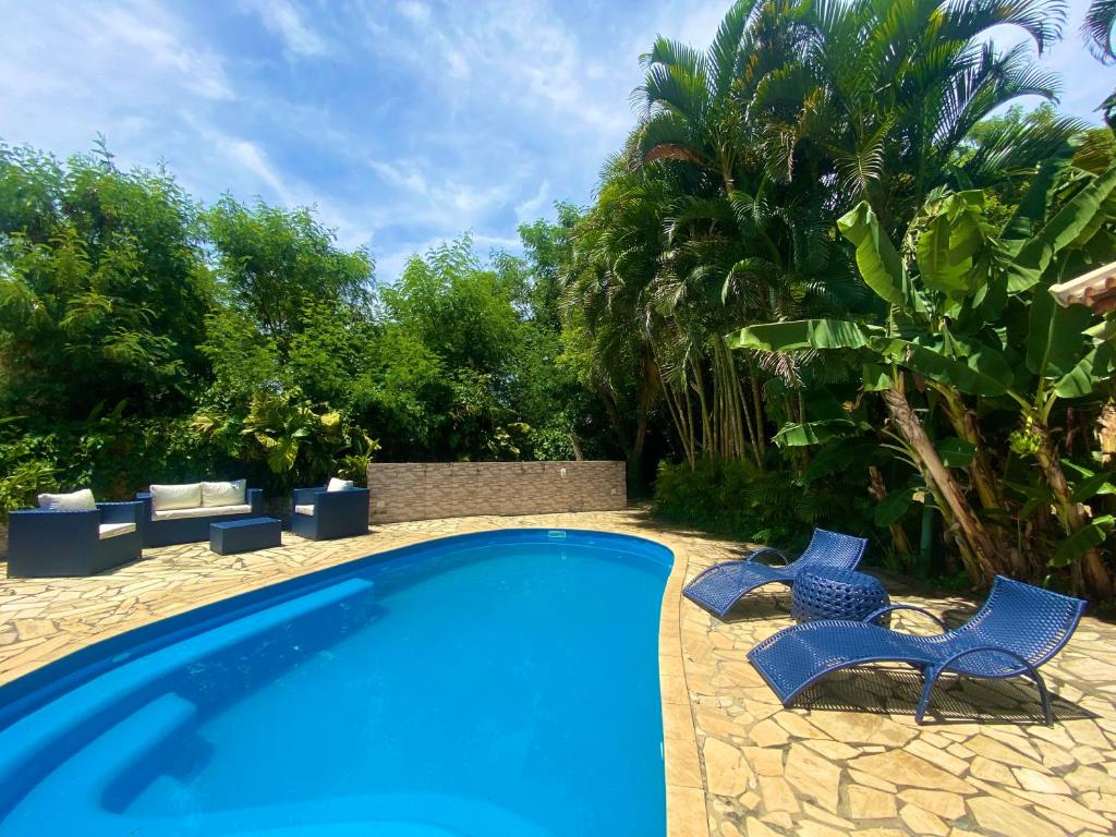 a swimming pool with two blue chairs next to it at Paraíso Geribá in Búzios