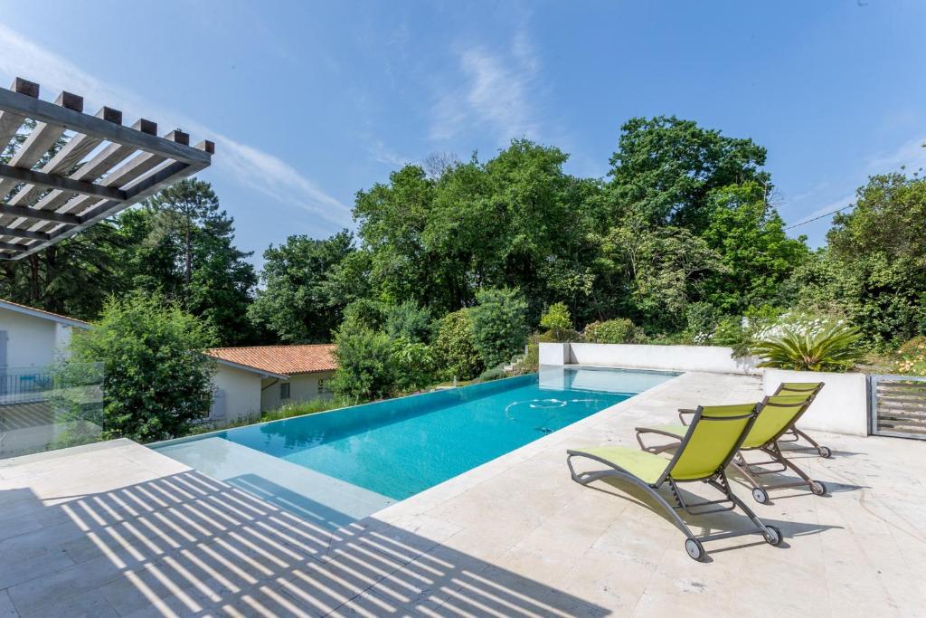 - une piscine avec 2 chaises longues à côté de la piscine dans l'établissement Villa Bichipau Park - Welkeys, à Bidart