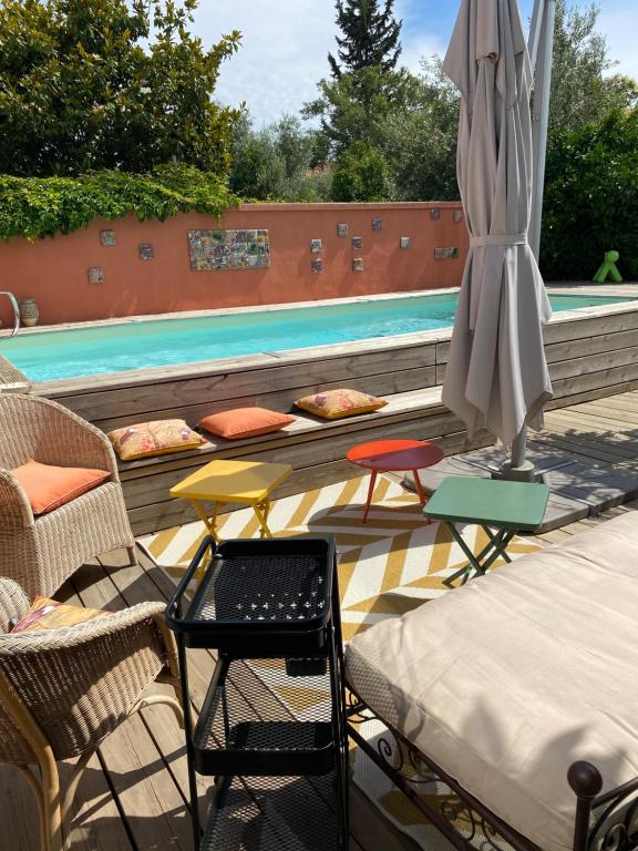 une terrasse avec une table, un parasol et une piscine dans l'établissement Chez Martine Côté Cité, à Carcassonne