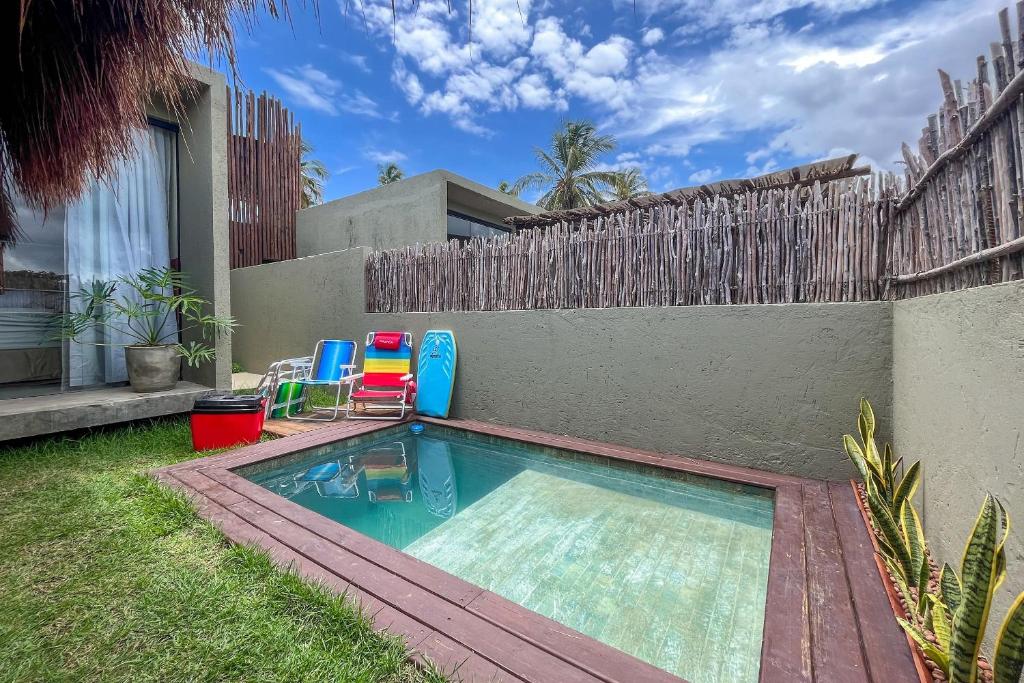 a small swimming pool with two chairs and a fence at Paraíso Patacho Riviera Casa 01 Villa 04 in Pôrto de Pedras