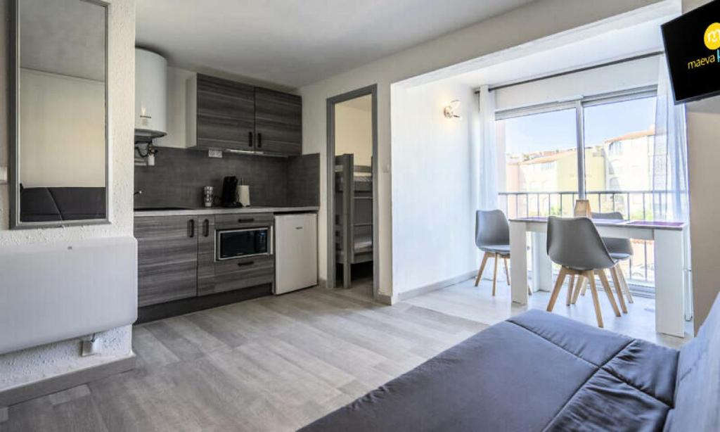 Cette chambre comprend une cuisine et une table avec des chaises. dans l'établissement Residence du Mail - Studio 4 personnes - Confort MAE-2784, au Cap d'Agde