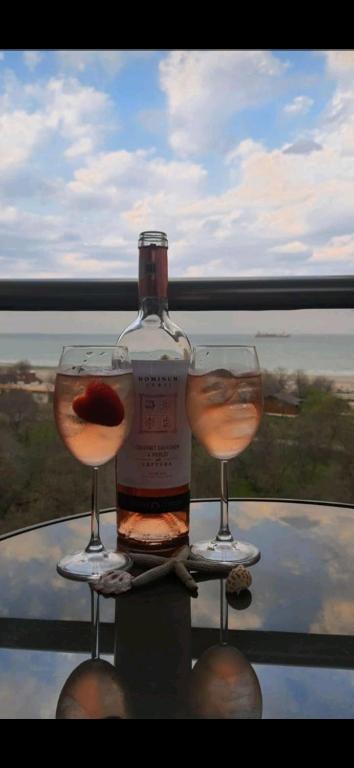 a bottle of wine and two glasses on a table at Frontal view by Twin Residence in Mamaia
