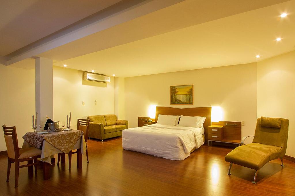 een hotelkamer met een bed en een tafel en stoelen bij Master Plaza Hotel in Barbacena
