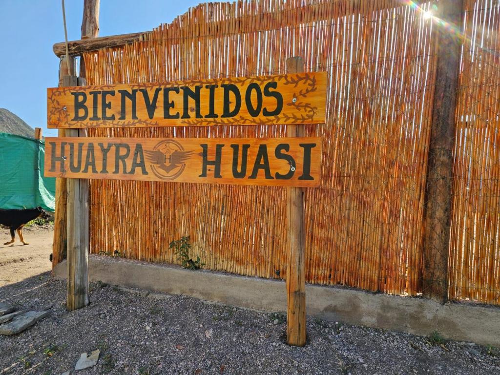 a sign in front of a fence with a sign for a huarma hut at Complejo Huayra Huasi in Villa Bustos
