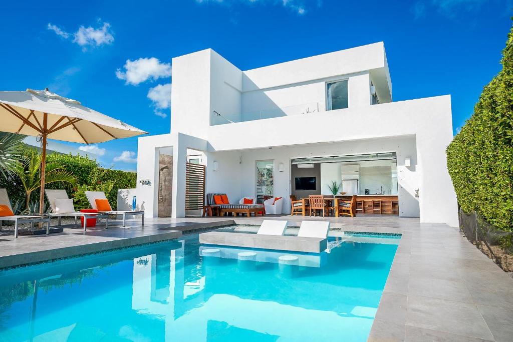 a villa with a swimming pool in front of a house at Oceanside 2 Bedroom Luxury Villa with Private Pool, 500ft from Long Bay Beach -V3 in Providenciales