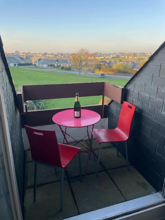 une table rose avec deux chaises et une bouteille de vin dans l'établissement Studio sur le Port du Crouesty, à Arzon