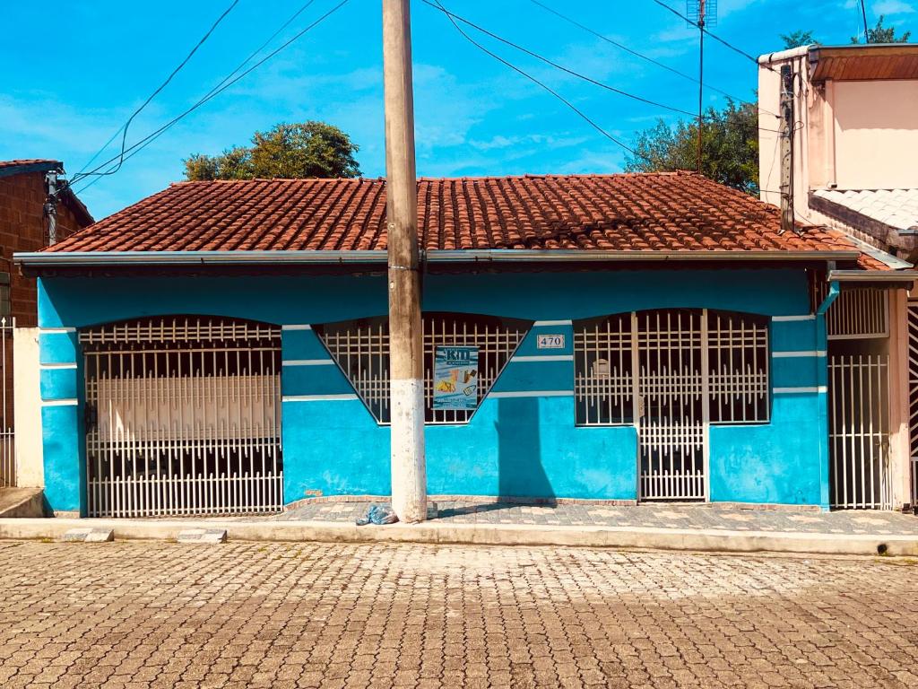 un bâtiment bleu avec deux fenêtres et un poteau dans l'établissement Casa & Hospedagem Carol, à Cachoeira Paulista