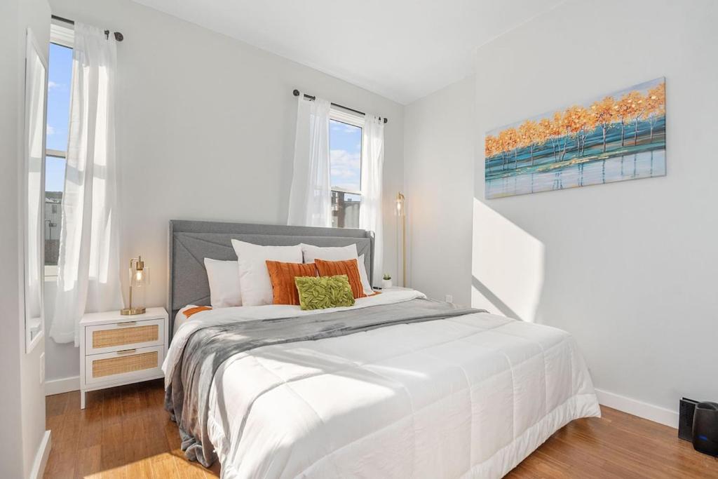 ein weißes Schlafzimmer mit einem großen weißen Bett und orangefarbenen Kissen in der Unterkunft Sleep like a King - OTR- Free Light Rail ! in Cincinnati
