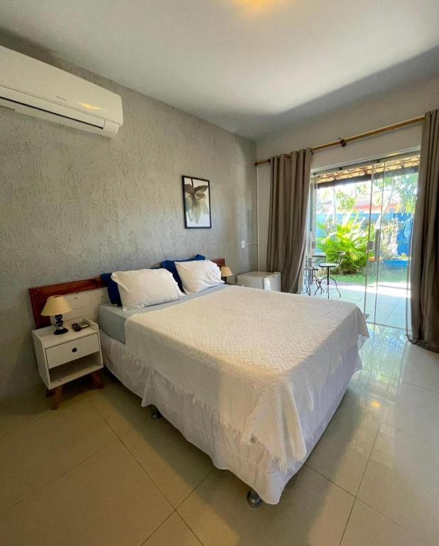 a bedroom with a large white bed and a window at Pousada Cielo Blu in Búzios