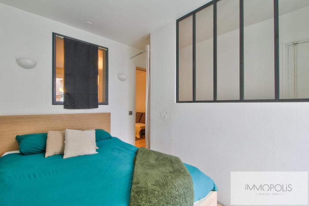 Un dormitorio con una cama azul y un espejo. en Bel appartement avec terrasse, en Clichy