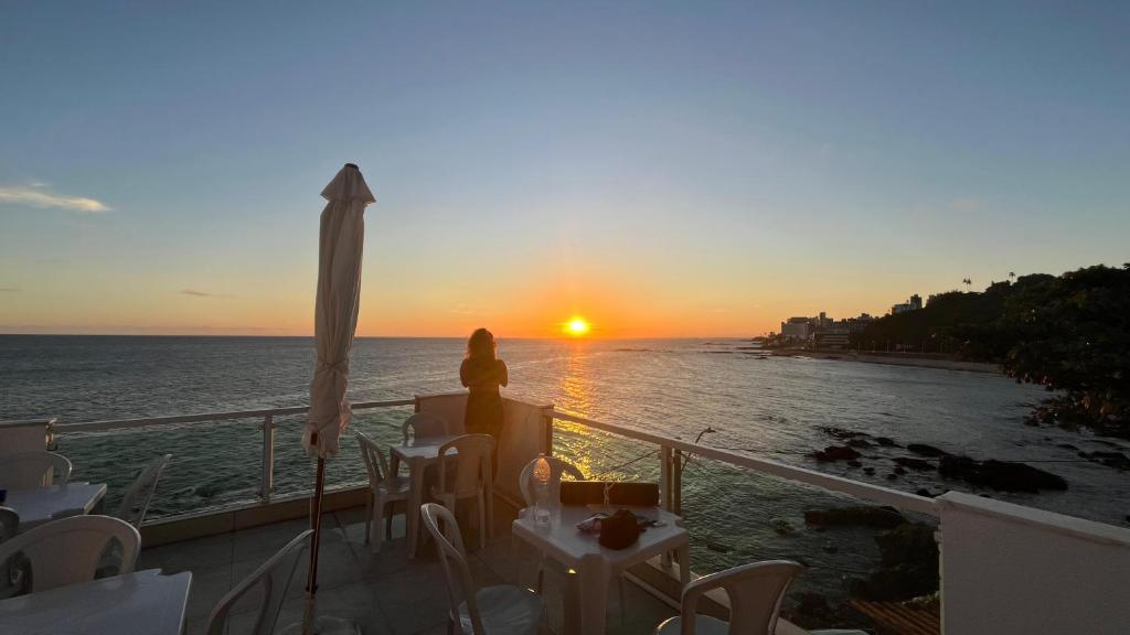 a woman sitting on a balcony watching the sunset at Hostel Feminino Sol de Maria in Salvador