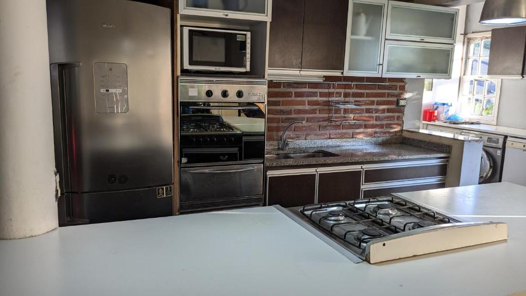 een keuken met roestvrijstalen apparatuur en een bakstenen muur bij Mishki Wasi - Dulce Hogar Magdalena in Magdalena