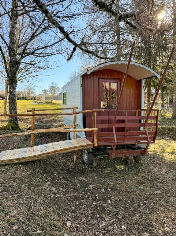 Une petite caravane avec une terrasse couverte et une clôture dans l'établissement La Corrèze en Roulotte, 3pers, à Saint-Pantaléon-de-Lapleau