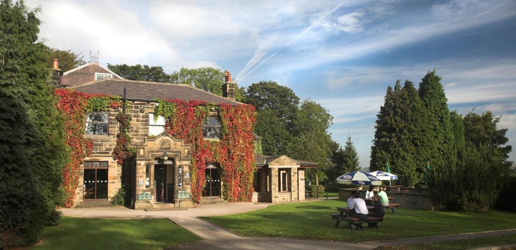 two people sitting on a bench in front of a house at Cubley Hall in Penistone