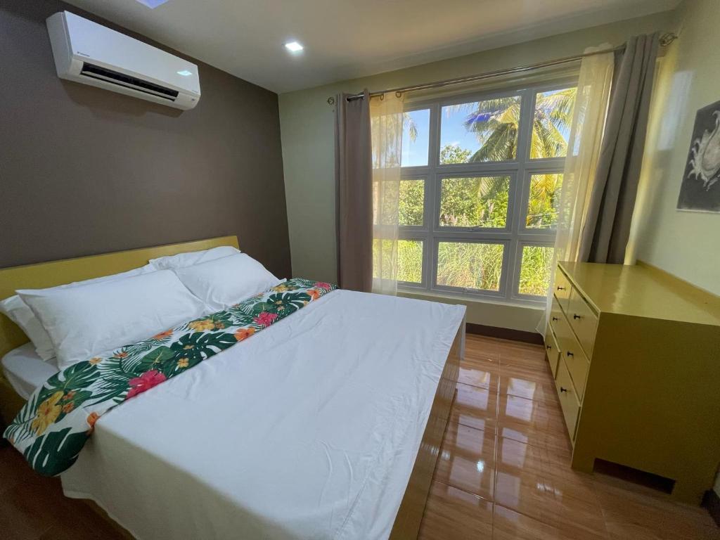 a bedroom with a white bed and a window at SahaLand Siargao Guest House in General Luna