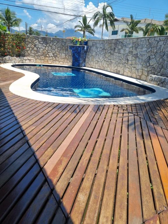 a swimming pool with a wooden deck and a bench at Casa de praia Peruibe in Peruíbe