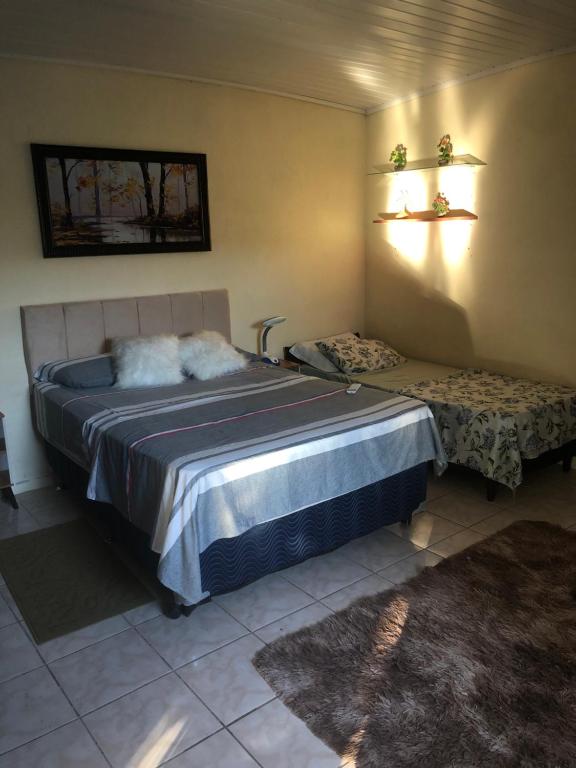 Un dormitorio con una cama grande y un banco en ella. en Pousada Fialho, en São Gabriel