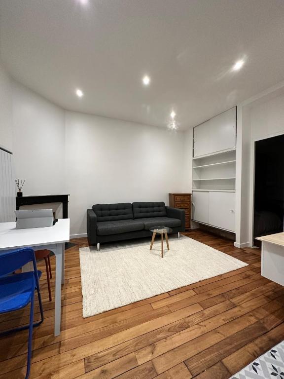 un salon avec un canapé noir et une télévision dans l'établissement Casa Preciosa, à Ivry-sur-Seine