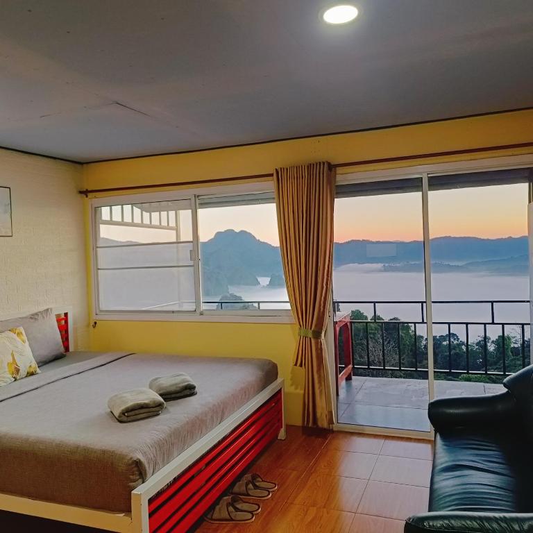 a bedroom with a bed and a large window at บ้านชมหมอก ภูลังกา in Ban Sakoen