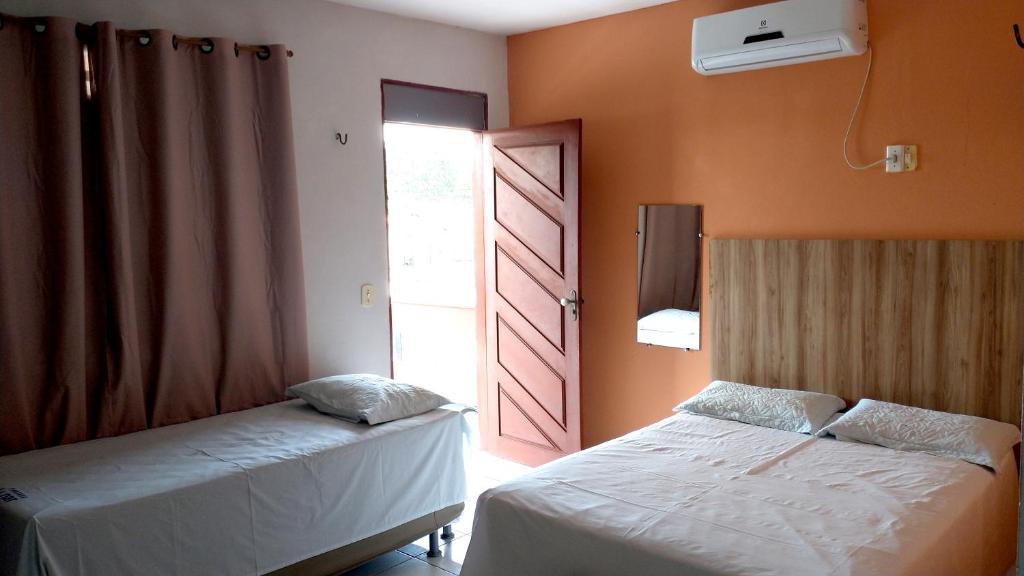 ein Schlafzimmer mit 2 Betten und einer offenen Tür in der Unterkunft Pousada Lunar in Parnaíba