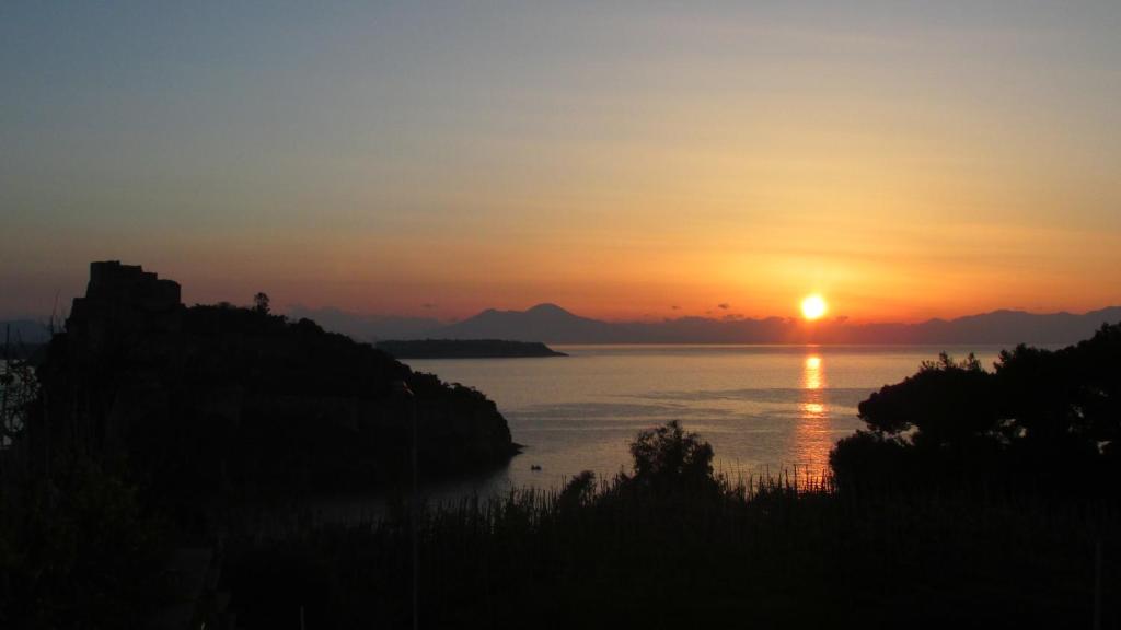 una puesta de sol sobre un gran cuerpo de agua en Cartaromana House en Ischia