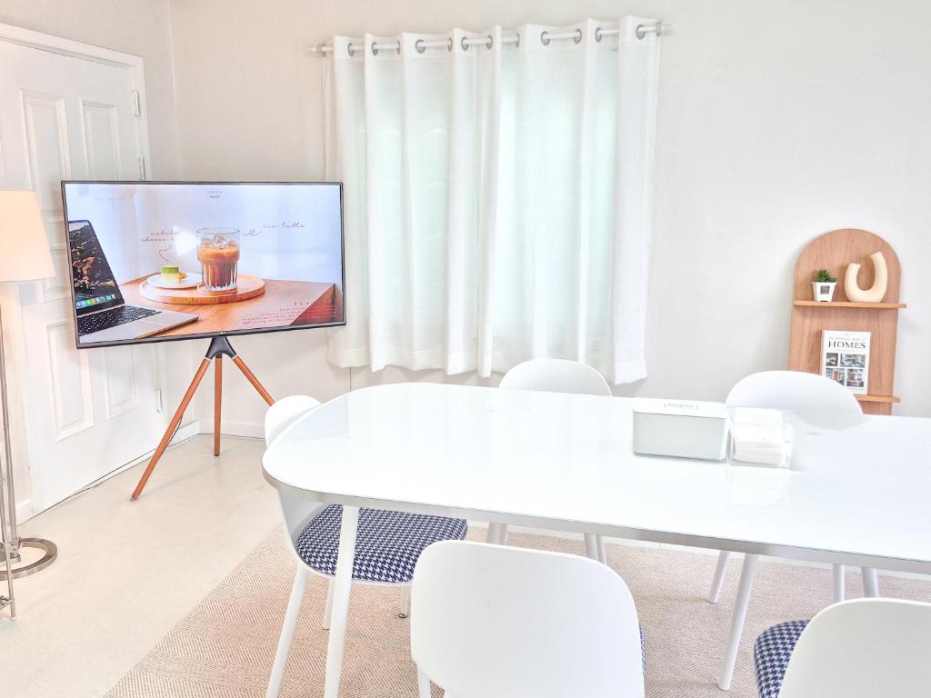 a living room with a tv and a table and chairs at Oiso Stay in Busan
