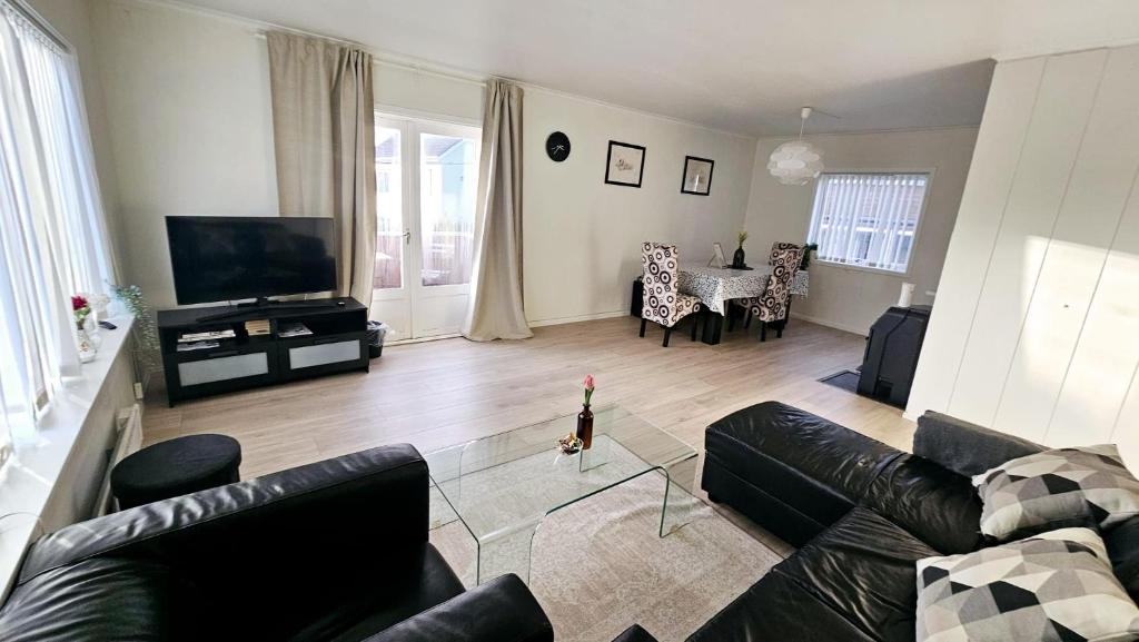 a living room with a couch and a television and a table at Koselig leilighet med balkong og parkering. in Stavanger