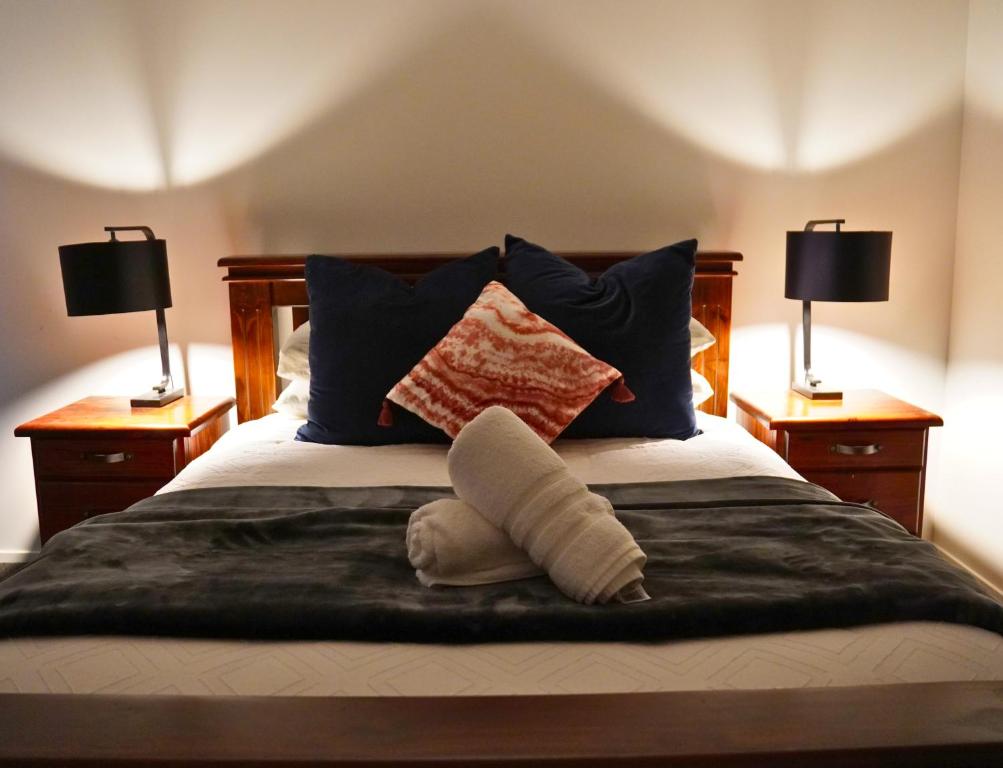 a bed with blue pillows and two lamps at Elite Escape Hawera in Hawera